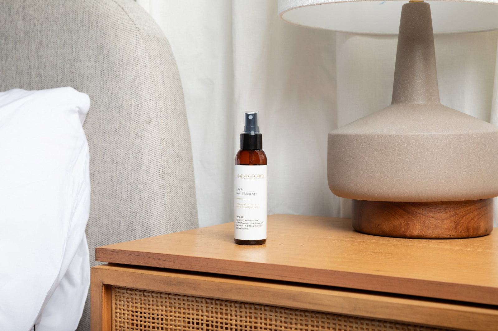 Linen scented room spray next to a pillow on a bed